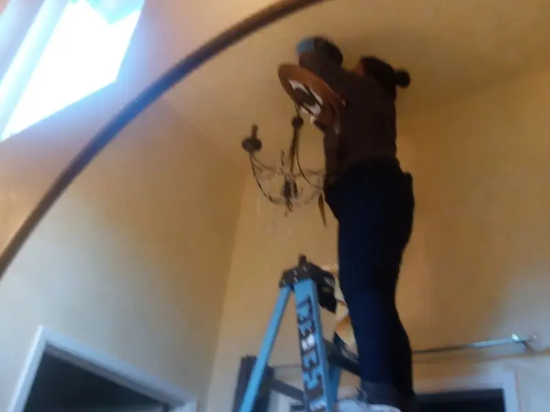 Electrician installing a chandelier in a Craig residence